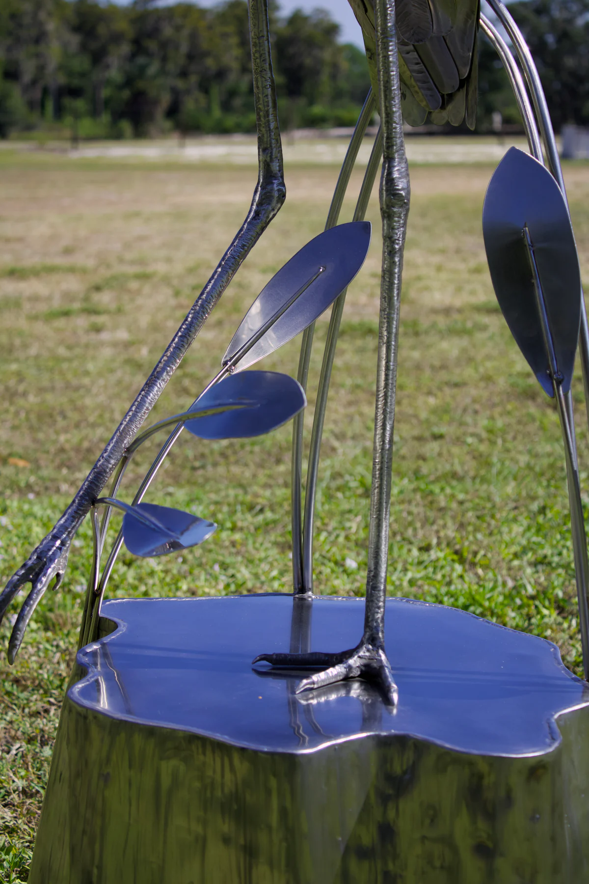 Close view of the crane's long legs, reed details, and steel base.