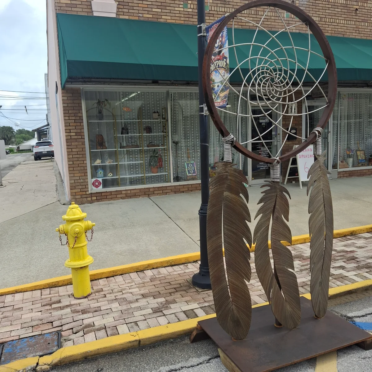 The full sculpture displayed on a sidewalk in front of a storefront, with a fire hydrant nearby.