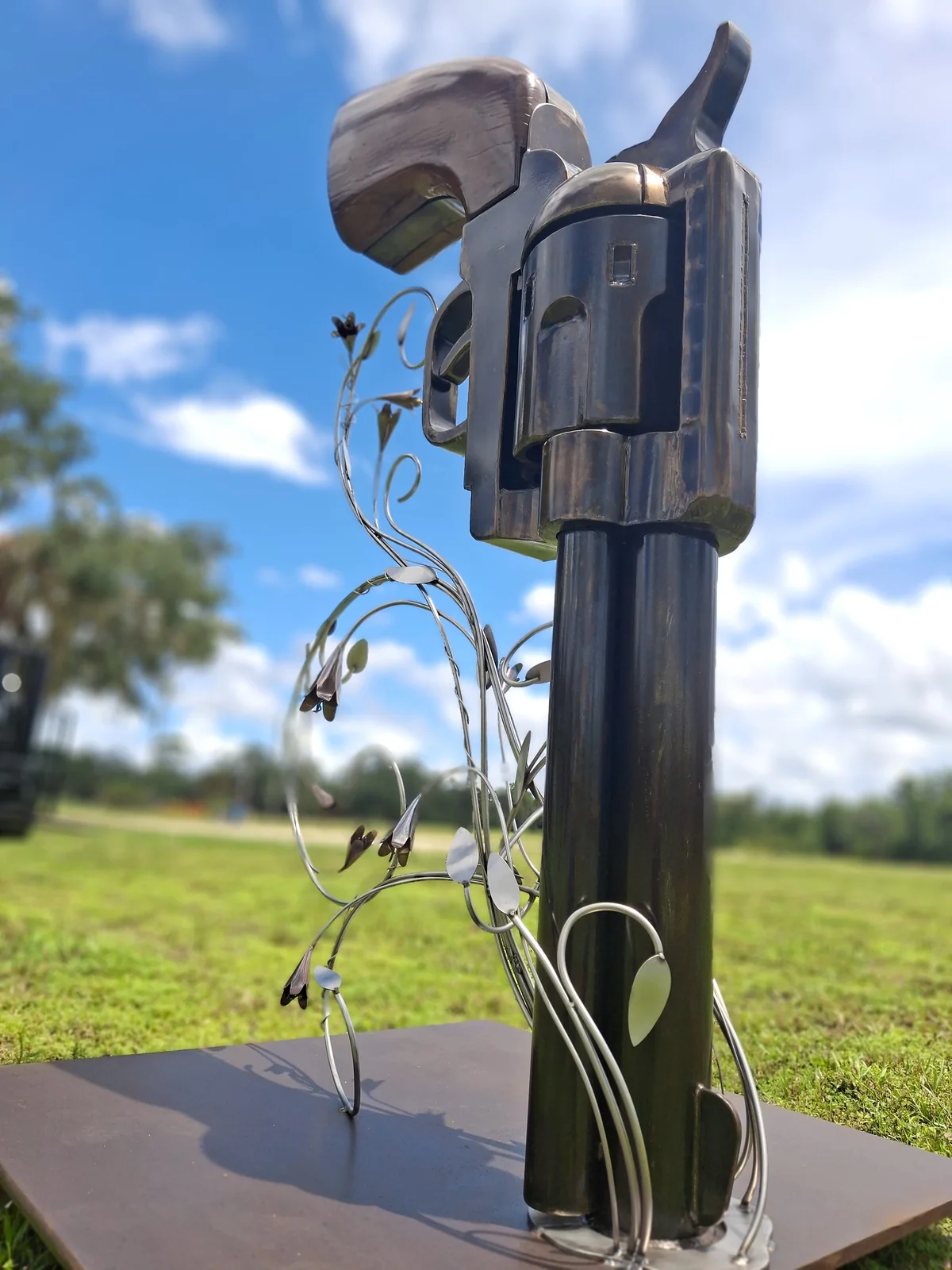 Close view of the wooden grip and revolver body with stainless steel vines and flowers beside it.