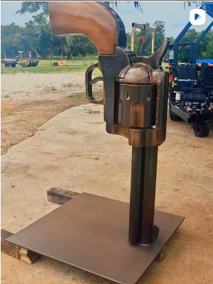 Assembled revolver sculpture displayed on its base outdoors.